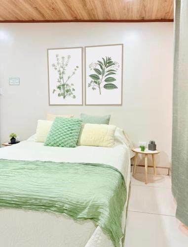 a white bedroom with a large bed with green sheets at Apartamento H González #12 in Alajuela