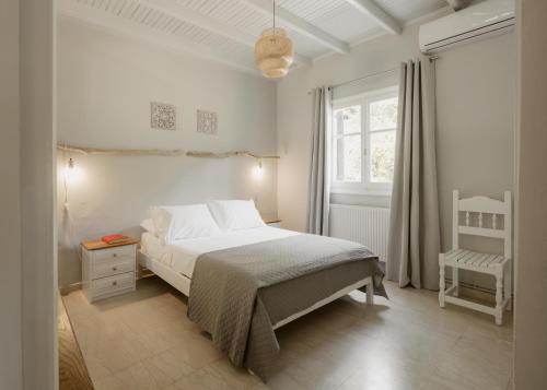 a white bedroom with a bed and a window at Mediterranean Haven in Paleokastritsa