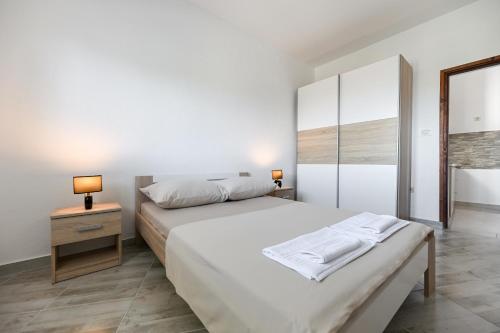 a white bedroom with a bed and a mirror at Costa apartment with private pool in Preko