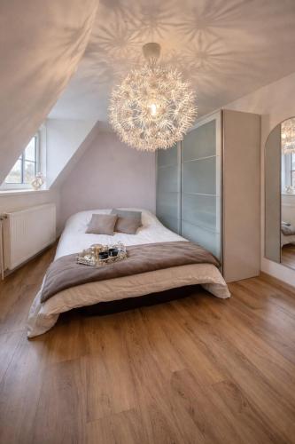 a bedroom with a large bed and a chandelier at Escapade chaleureuse in Sequedin