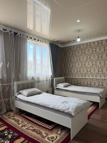 a bedroom with two beds and a window at Hidden Valley Guesthouse in Toguz-Bulak