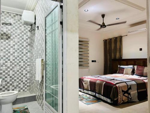 a bedroom with a bed and a bathroom with a toilet at T-Roys Apartments in Accra