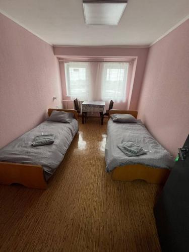 a room with two beds and a table and a window at Оазис in Lutsk