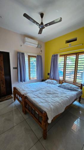 a bedroom with a large bed with a ceiling fan at Aadhya Serenity - Private Villa near Ecobeach Honnavar in Honāvar