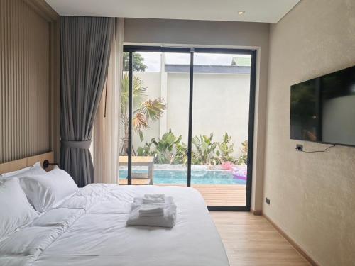 a bedroom with a bed and a view of a pool at Villa Tierra Pattaya in North Pattaya