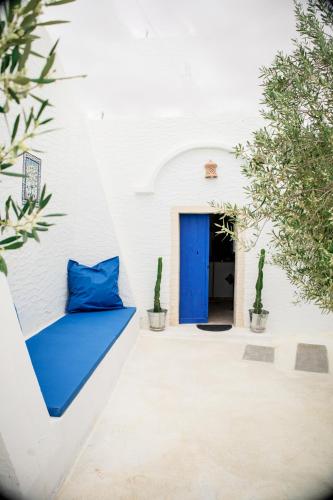 a blue pillow sits on a white wall with a blue door at Menzel LellaMina in Houmt Souk