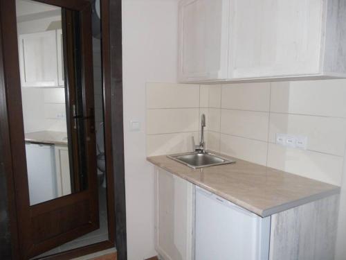 a white kitchen with a sink and a door at EP Apartment in Mgzavrebi Bakuriani in Bakuriani
