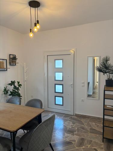 a dining room with a table and chairs and a door at Villa Pano Salamina in Ambelákia