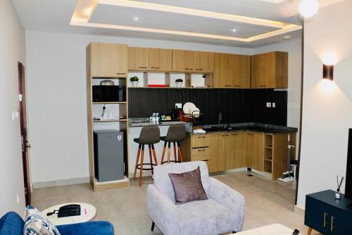 a living room with a kitchen and a couch and a chair at House 10 Apartments in Abuja