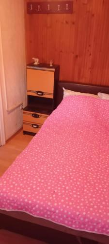 a bed with a pink comforter in a bedroom at Vila Sofija in Vinci
