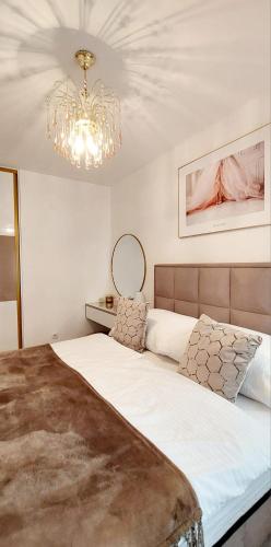 a bedroom with a large bed with a chandelier at Royal Apartman in Banja Koviljača