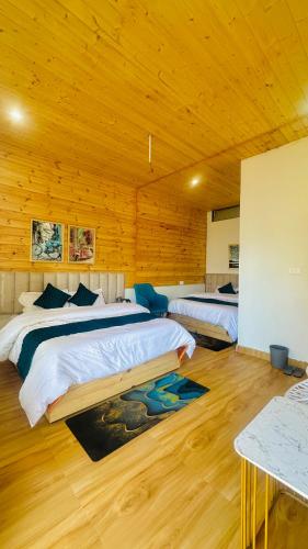 two beds in a room with wooden walls at Canvas stay by Fairlink in Jāmb