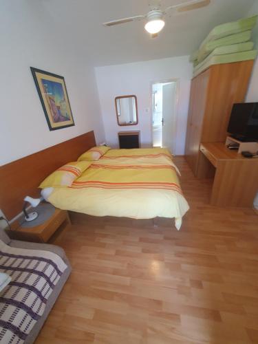 a bedroom with a bed and a desk and a television at Marica Dedić in Barbat na Rabu