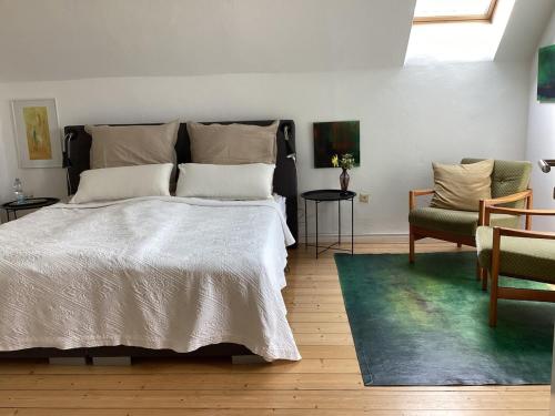 a bedroom with a white bed and two chairs at Hahnhaus in Burscheid