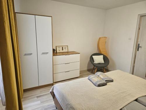 a bedroom with a bed and a cabinet and a chair at Apartament Wiejska Sielanka in Ryn