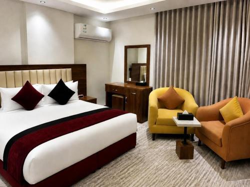 a hotel room with a bed and two chairs at ساتورن هاوس للشقق الفندقية in Tabuk