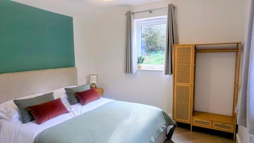 a bedroom with a white bed with red pillows and a window at Yr Hen Stabl - The Old Stable in Llangerniew