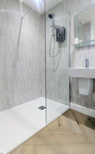 a shower with a glass door next to a sink at Yr Hen Stabl - The Old Stable in Llangerniew