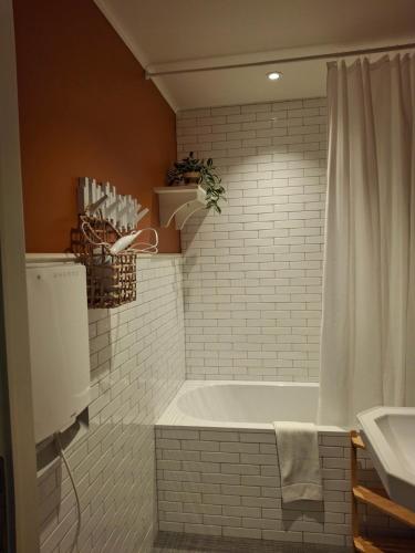 a white bathroom with a tub and a sink at Het Koetshuis, op 50m van zee, voor 5 personen, centrum Westende BAD, alle comfort in Middelkerke