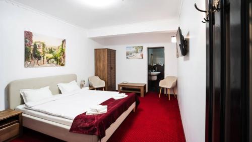 a bedroom with a white bed and a red carpet at MAX International Hotel in Râşnov