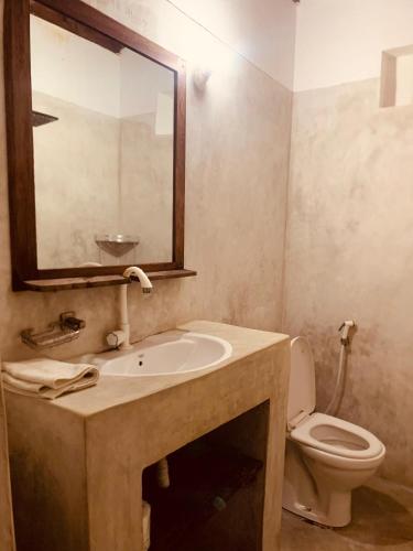 a bathroom with a sink and a toilet and a mirror at Villa Milu in Jambiani
