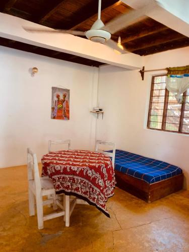 a room with a bed and a table and chairs at Villa Milu in Jambiani