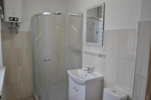 a white bathroom with a shower and a sink at Retro Ķemeri in Jūrmala