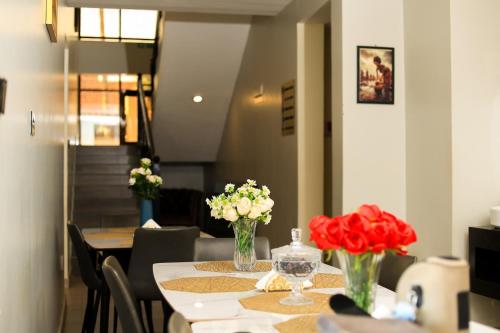 a table with red and white flowers in vases on it at Travellers Palace Hotel in Kampala