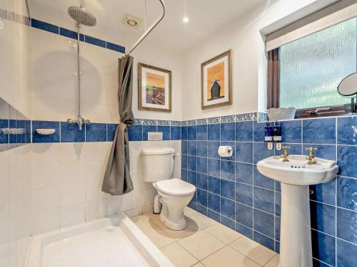 a blue tiled bathroom with a toilet and a sink at 1 Bed in Isle Of Arran oc-ca272 in Pirnmill