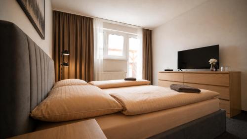 ein Schlafzimmer mit Bett, Fernseher und Fenster in der Unterkunft HLBOKÉ Hotel & Lesopark in Bojnice