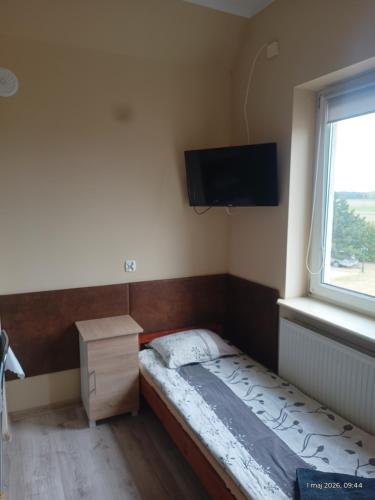 a small bedroom with a small bed and a window at Apartamenty Sokółka II in Sokółka
