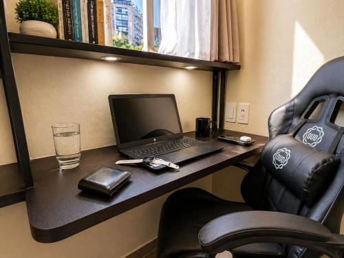 a desk with a laptop and a glass of water at Habitación individual con baño privado a 3 Min del Estadio Azteca-Banorte y muy cerca de zona de hospitales in Mexico City