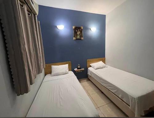 two beds in a room with a blue wall at Marina Hotel in Ciudad del Este