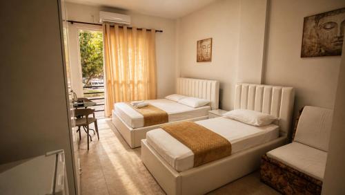 a bedroom with two beds and a table and a chair at Villa Arli&Eris in Vlorë