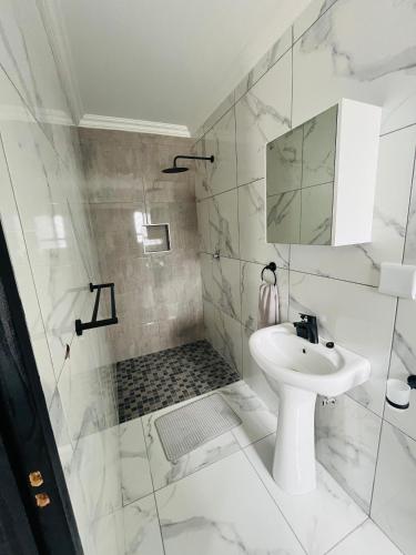 a white bathroom with a sink and a mirror at Oregano Estate in Swakopmund