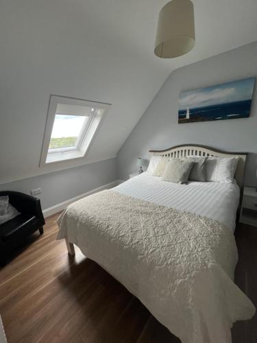 a bedroom with a large white bed with a window at Atlantic way Apartment 1 in Breaghwy