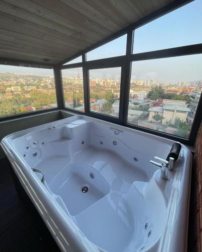 a large white bath tub in a room with windows at Brooch Boutique Hotel in Tbilisi City