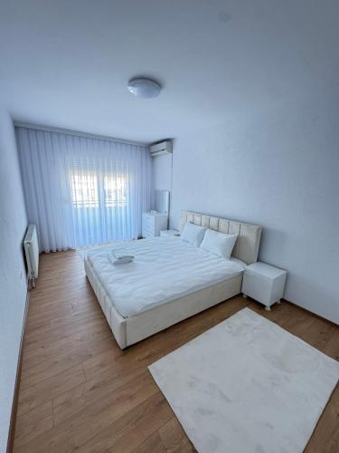 a white bedroom with a large bed and a window at Rubinas Apartment in Prizren