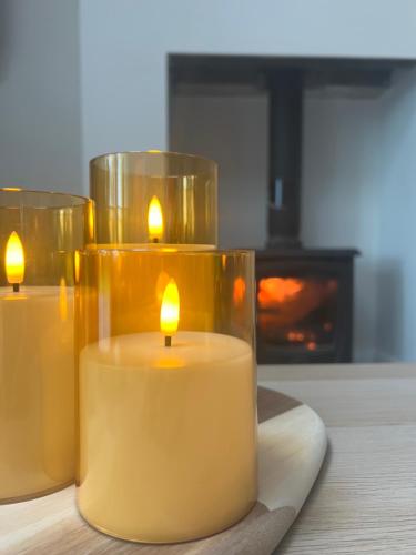 three candles sitting on a table in front of a fireplace at The Cuckoos Nest - 2 bedroom in Headford