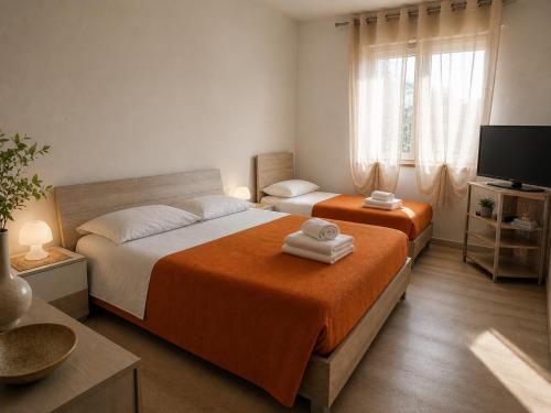 a bedroom with two beds and a flat screen tv at Home Istria 81 in Trieste
