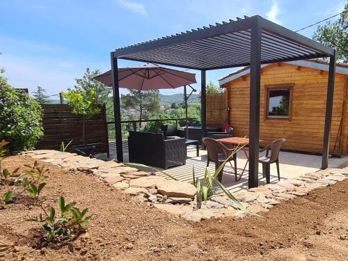 a patio with a table and an umbrella at Charmant chalet en bois - Ardèche in Joyeuse