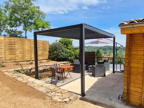 a black pavilion with a table and chairs on a patio at Charmant chalet en bois - Ardèche in Joyeuse
