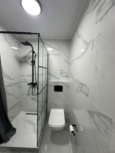 a white bathroom with a toilet and a shower at Renovat si stilat pentru un sejur de exceptie in Ungheni