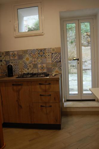 a kitchen with a stove and a window and a door at La Dimora Sicula in Modica