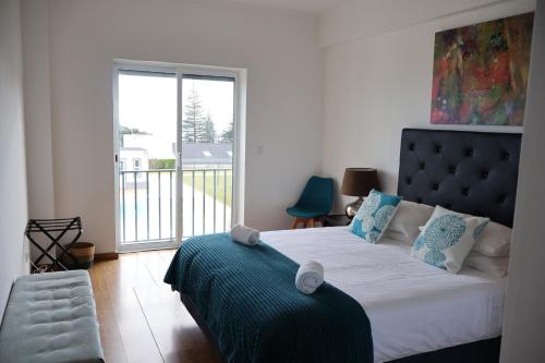 a bedroom with a bed and a large window at CASA SIMBA , where the fun begins in Ponta Delgada