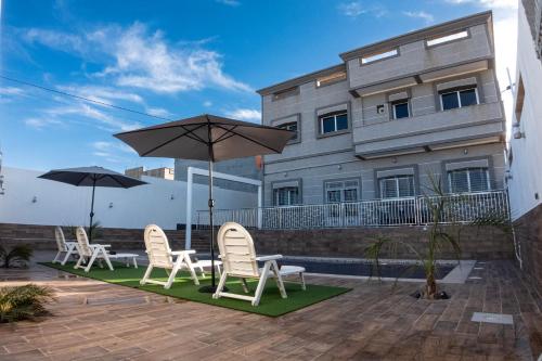a patio with chairs and umbrellas in front of a building at Villa Raha in Selouane