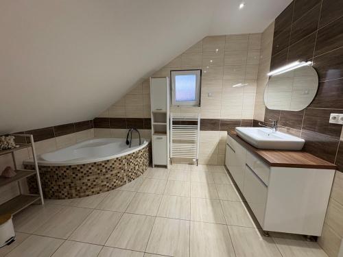 a bathroom with a tub and a sink and a bath tub at Attic Apartment in Kočovce