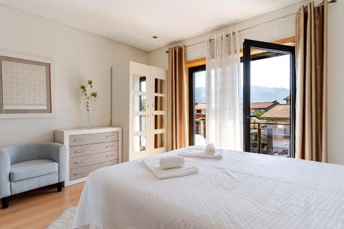 a bedroom with a bed and a chair and a window at Casa entre Rios in Alpendurada