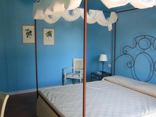 a bedroom with a canopy bed with blue walls at Etna Hotel in Giarre