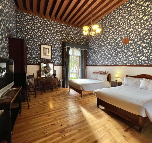 a bedroom with two beds and a tv in it at Hacienda Soltepec Suites Campo de Golf in Huamantla